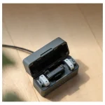 کیس شارژ باز DJI Mic Mini 2S روی میز چوبی به همراه فرستنده ها و کابل شارژ