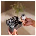 فرستنده کوچک DJI Mic Mini 2S در دست، در کنار کیس شارژ باز
